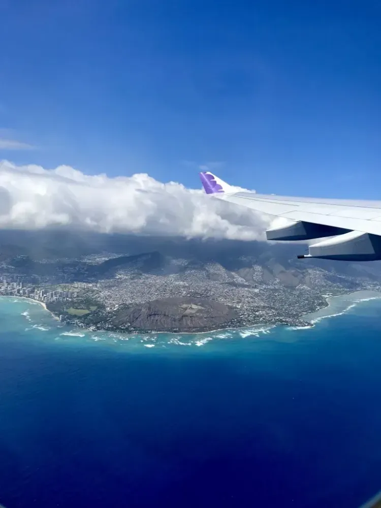 hawaiian airlines flying over diamond head crater and ocean.